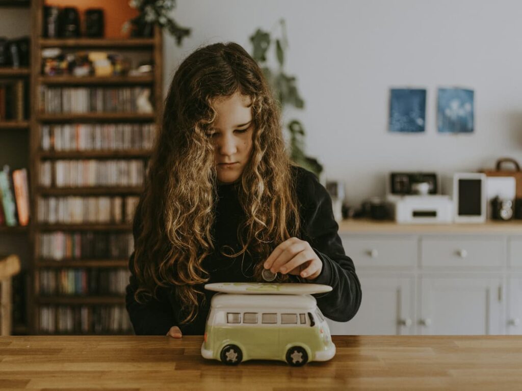 Young girl saving coins in a piggy bank as part of financial literacy learning